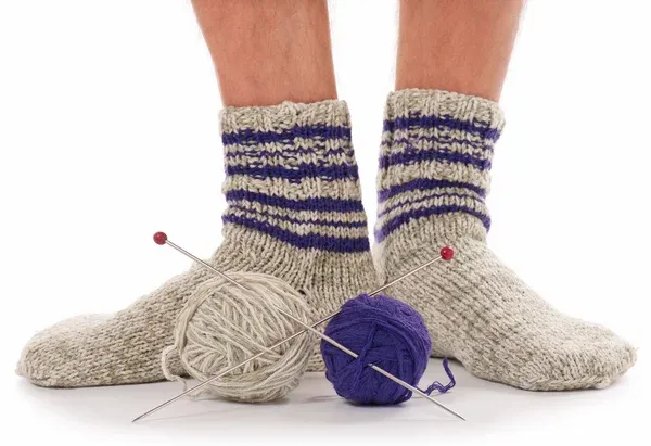 Feet of a man wearing knitted socks, alongside knitting material Feet of a man wearing knitted socks, alongside knitting material