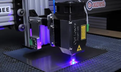 CNC laser engraving machine with a focused purple beam set up for engraving custom leather patches