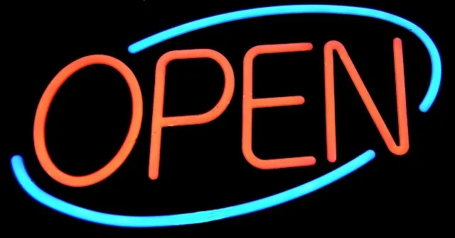 A neon sign hanging inside a shop window