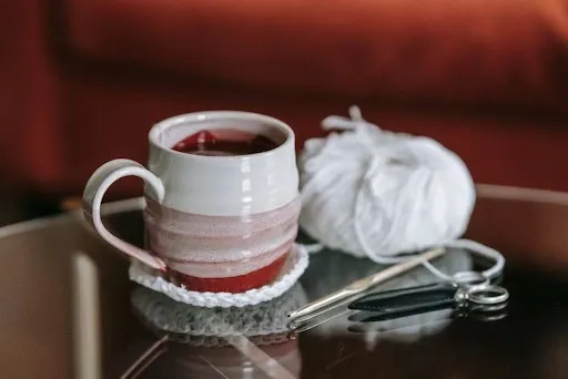 Mug resting on a finished white crochet coaster next to yarn, hook, and scissors used to make and finish crochet coasters.jpg Mug resting on a finished white crochet coaster next to yarn, hook, and scissors used to make and finish crochet coasters.jpg