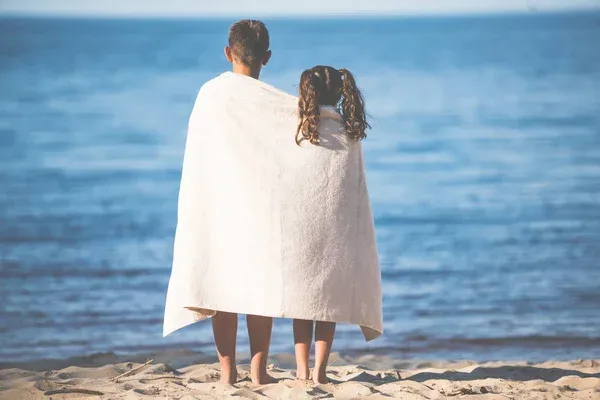 Kid wrapped in a white towel standing on a beach Kid wrapped in a white towel standing on a beach