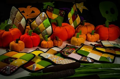 Fall pumpkin table runner style inspiration- quilted patchwork potholders and fabric pumpkins in orange, green, and gold autumn colors, ideal for Halloween and Thanksgiving quilting projects.png