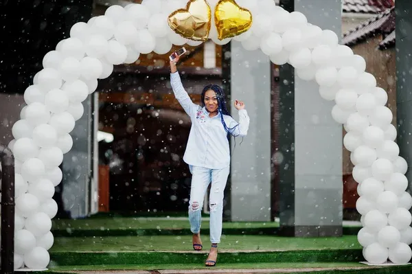 Girl in all white standing under an all-white balloon arch Girl in all white standing under an all-white balloon arch