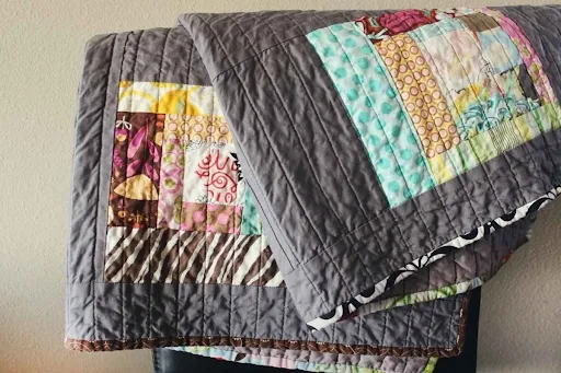 Reversible quilted table runner folded to show a neutral gray year-round side and a colorful patchwork fall side, perfect for double-duty autumn table decor.png