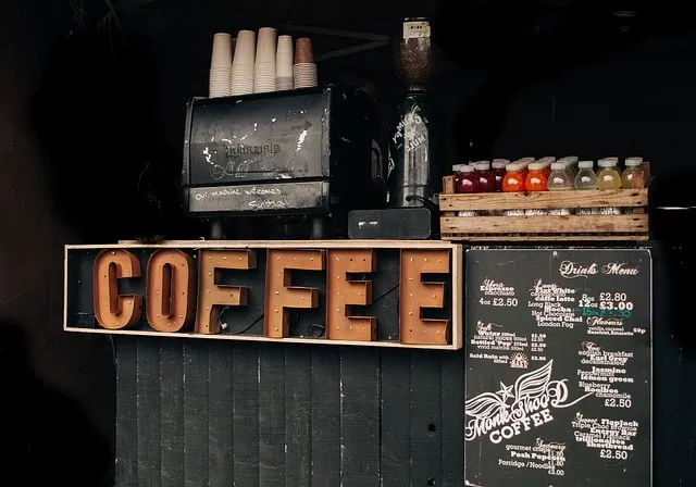 A rustic coffee bar counter with a large vintage-style COFFEE sign and handwritten drinks menu