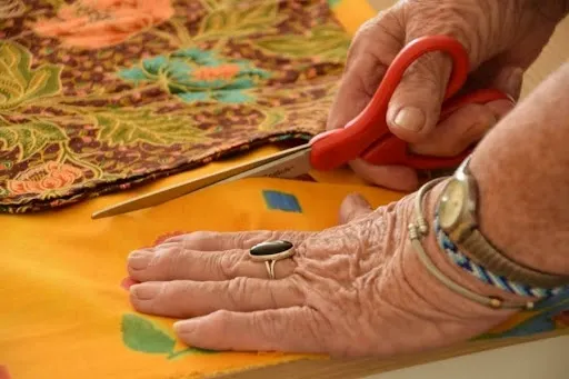 Crafter cutting fabric shapes and stabilizer to make an applique patch, showing precise scissor work for a clean applique edge.jpg Crafter cutting fabric shapes and stabilizer to make an applique patch, showing precise scissor work for a clean applique edge.jpg