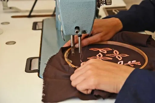 Embroidery machine stitching a satin border on a hooped applique patch design, sewing the finishing edge stitch.jpg Embroidery machine stitching a satin border on a hooped applique patch design, sewing the finishing edge stitch.jpg