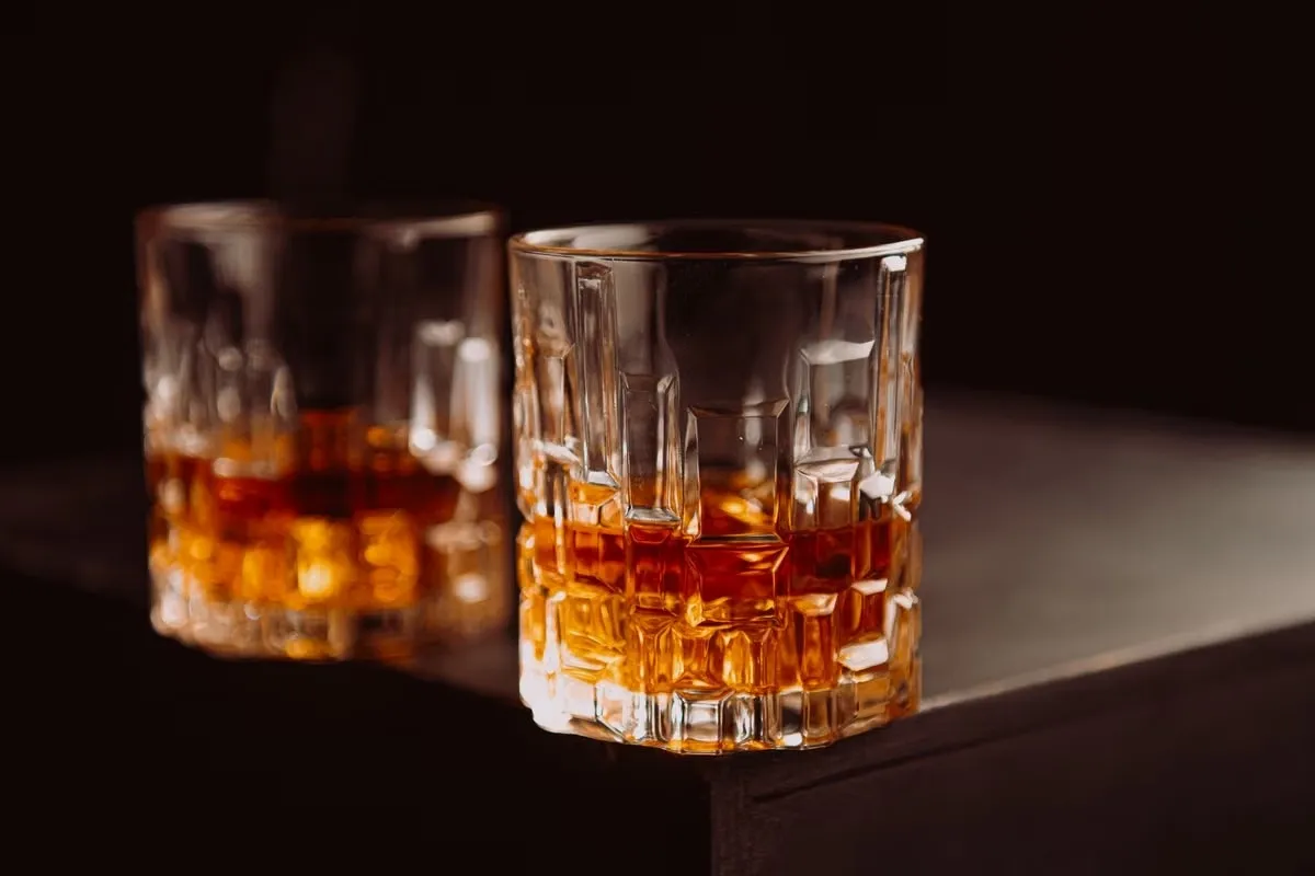 Crystal whiskey glasses filled with amber whiskey on a dark table, a classic 50th birthday gift for men who enjoy a good pour Crystal whiskey glasses filled with amber whiskey on a dark table, a classic 50th birthday gift for men who enjoy a good pour