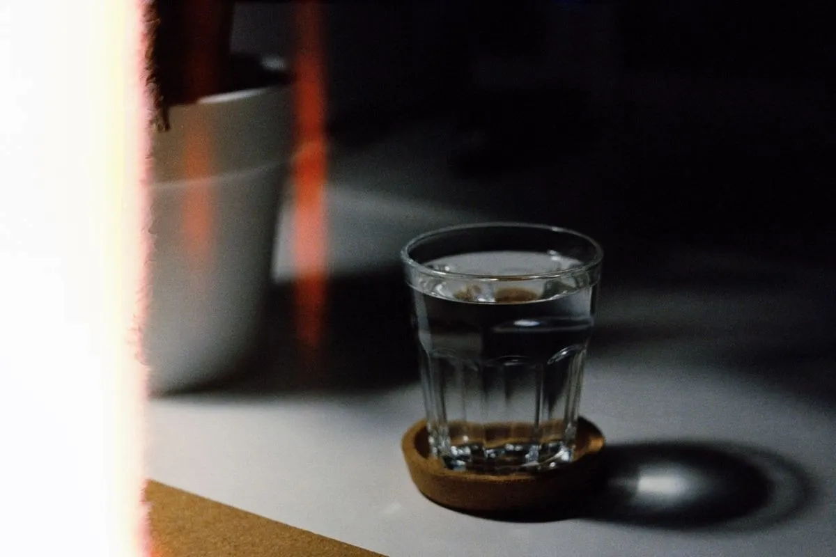 Cold glass of water resting on a dark soft coaster that absorbs condensation without scratching the table Cold glass of water resting on a dark soft coaster that absorbs condensation without scratching the table