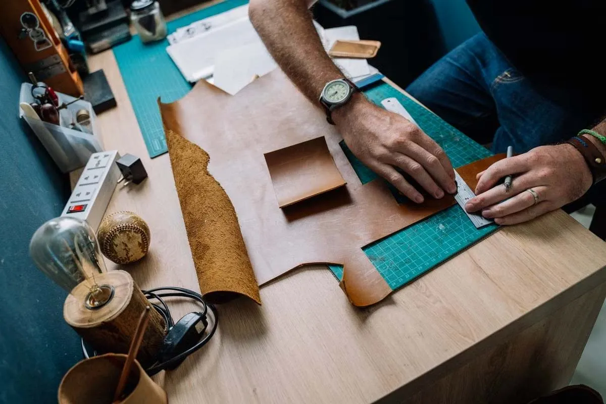 Hands cutting vegetable-tanned leather with a ruler and knife, the first step in making DIY leather coasters Hands cutting vegetable-tanned leather with a ruler and knife, the first step in making DIY leather coasters