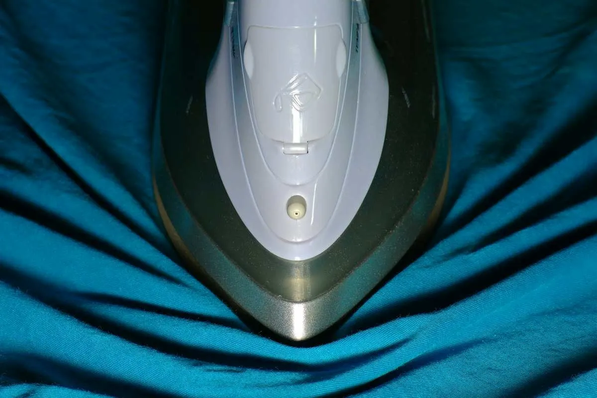 Clothes iron gliding over woven fabric on a low heat setting, showing the gentle pressing approach for burlap.jpg