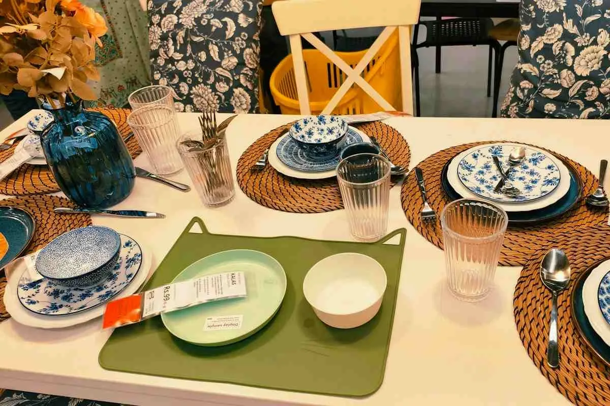 Dining table set with woven placemats, blue patterned plates and glassware at each seat.jpg Dining table set with woven placemats, blue patterned plates and glassware at each seat.jpg