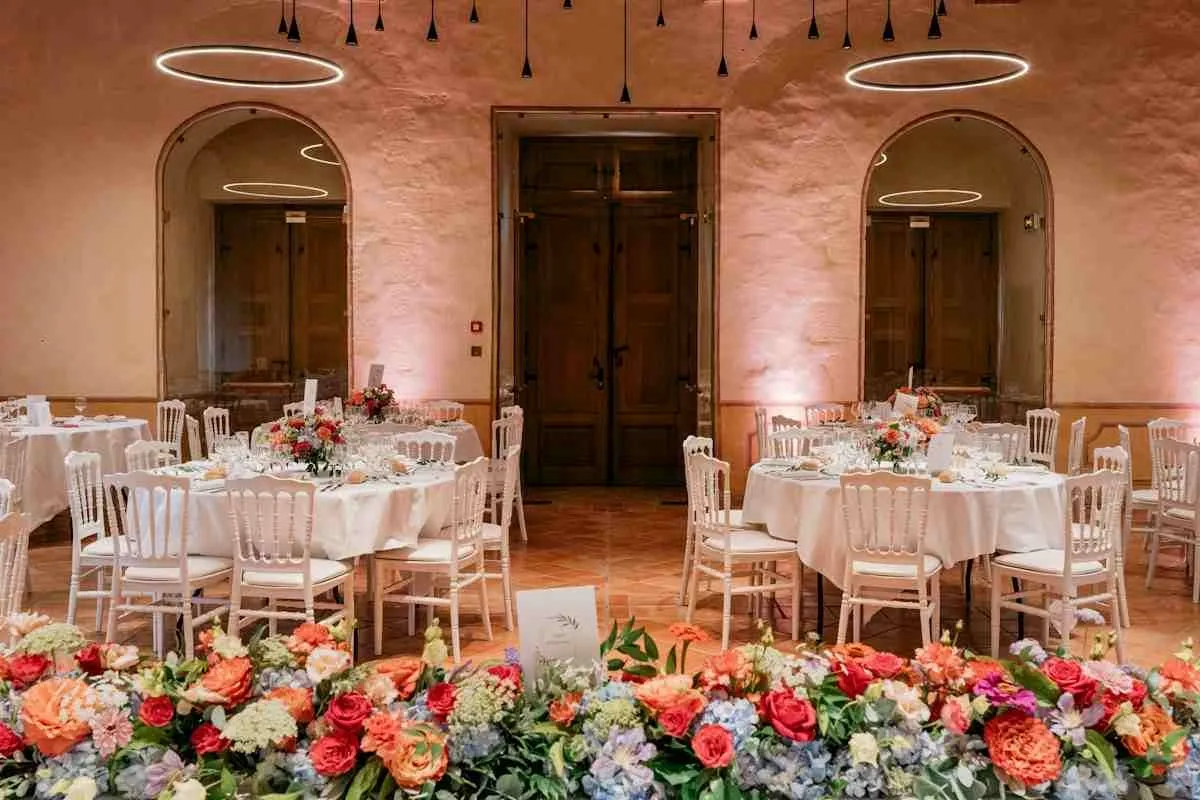 Large round banquet tables with white linens and floral centerpieces at a wedding reception.jpg Large round banquet tables with white linens and floral centerpieces at a wedding reception.jpg