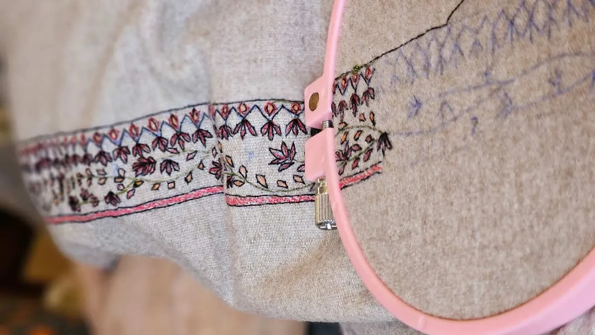 Embroidery hoop setup with detailed stitching progress on a base fabric during a custom patch build.jpg