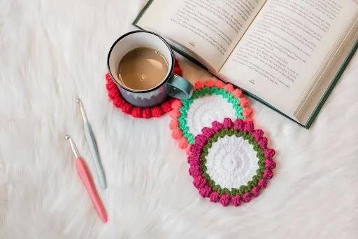 Coffee cup resting on a hand-crocheted coaster next to an open book, showing a functional cotton crochet coaster protecting a wooden table.jpg Coffee cup resting on a hand-crocheted coaster next to an open book, showing a functional cotton crochet coaster protecting a wooden table.jpg