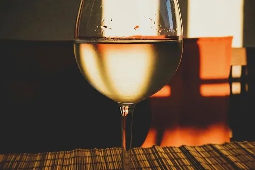 Clear stemmed wine glass on a wooden table, showing the base a quilted wine glass coaster pattern must accommodate with a fitted opening and 1:4 to 1:2 inch of ease.jpg