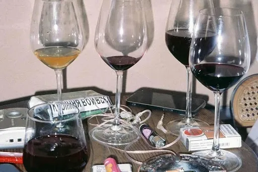 Wine glasses filled with red wine on a wooden table, showing the tabletop setting where a quilted wine glass coaster pattern or slipper protects the surface.jpg