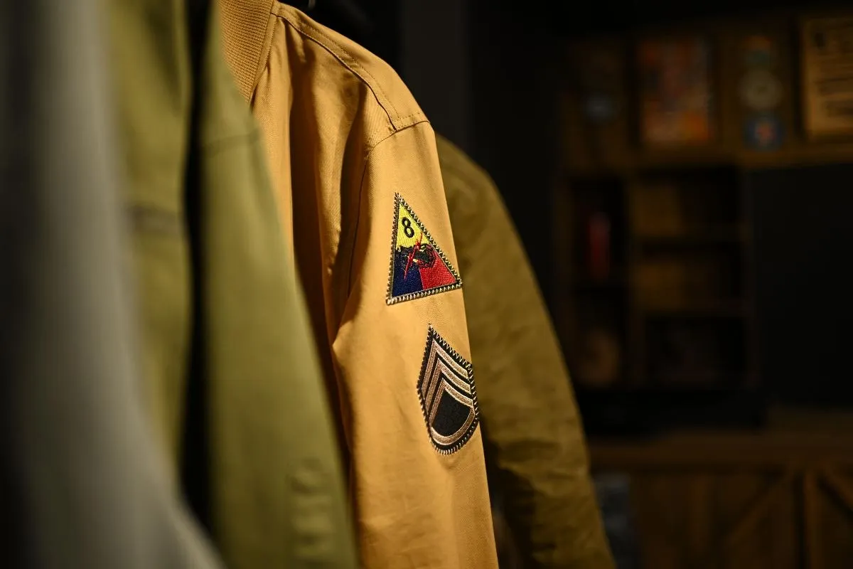 Military-style jacket sleeve showing a collection of embroidered Velcro patches in different sizes.jpg