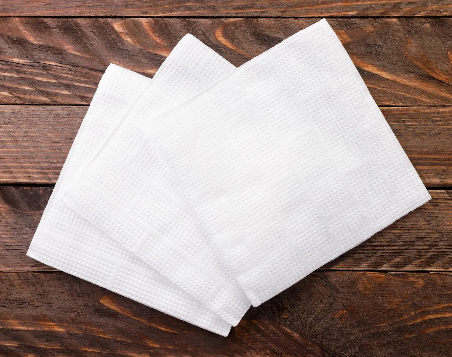 White paper napkins close up on wooden background. the view from top