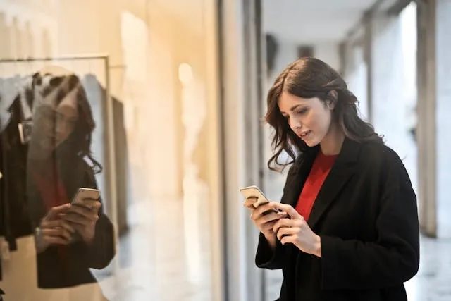 a person looking at their phone in front of a shop window for how to improve customer experience in retail stores