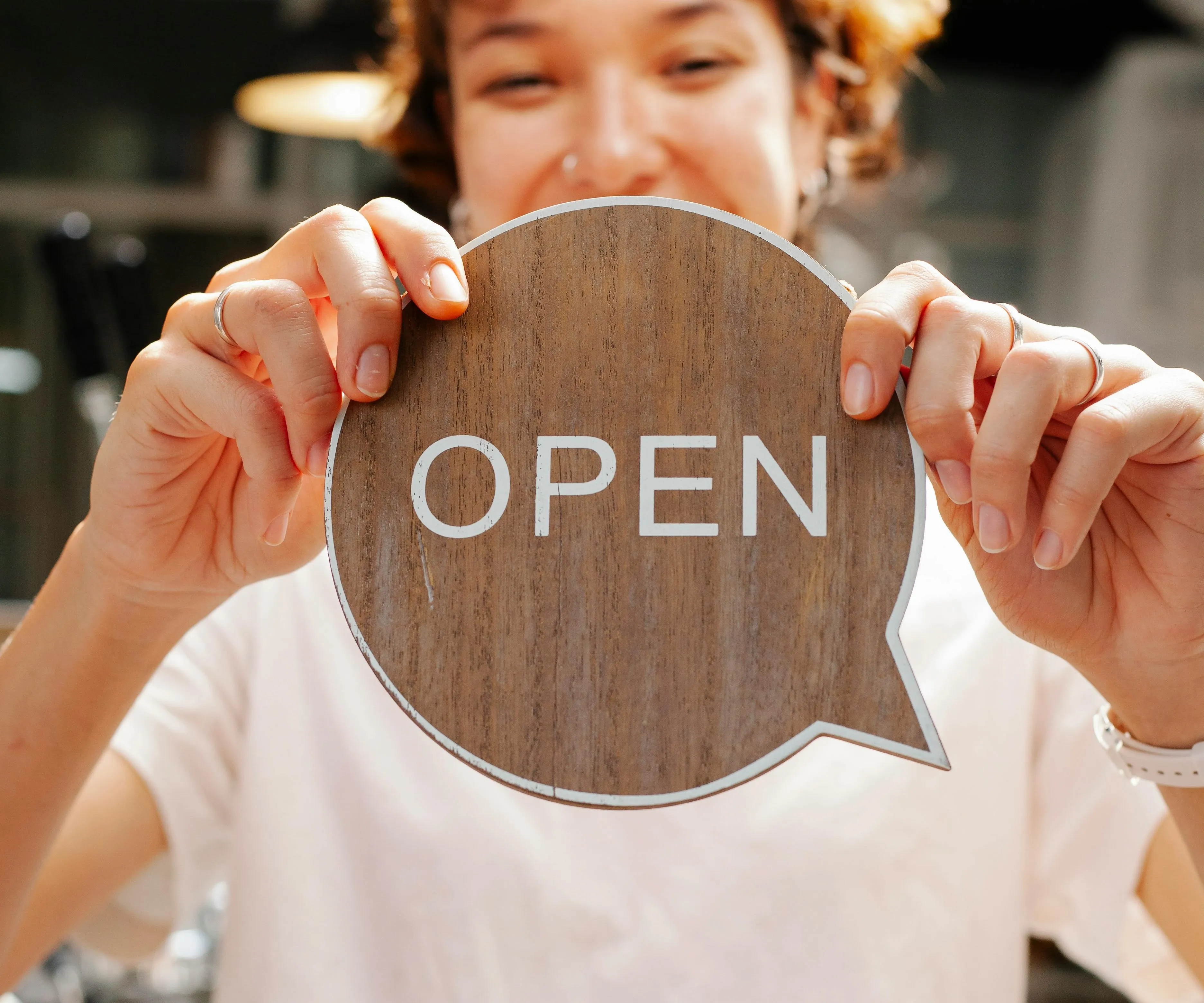 a person holding up a wooden open sign for restaurant branding ideas