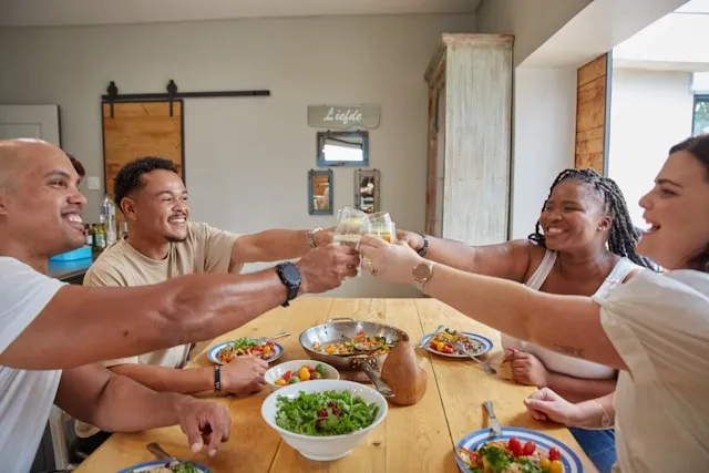 people raising a toast around a table for dinner party essentials