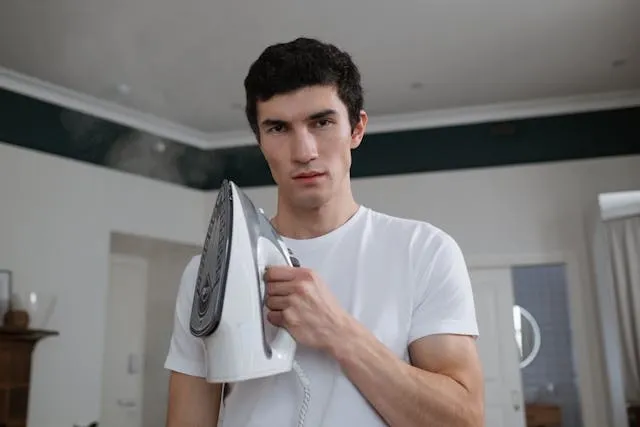 a person holding an iron for how to use iron on patches for jeans