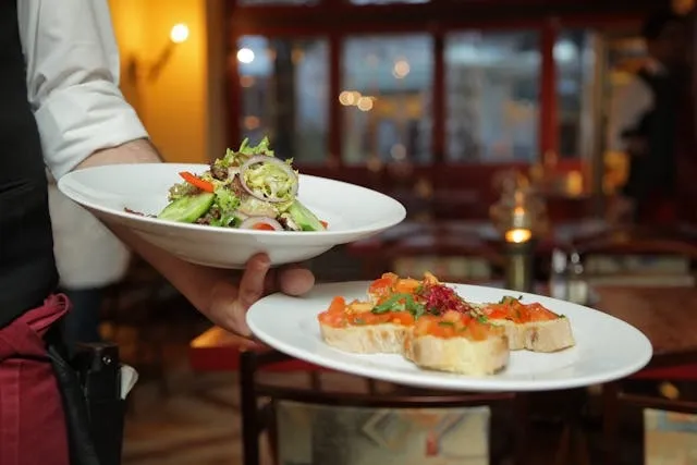 a person holding white dishes with prepared food for equipment for restaurant