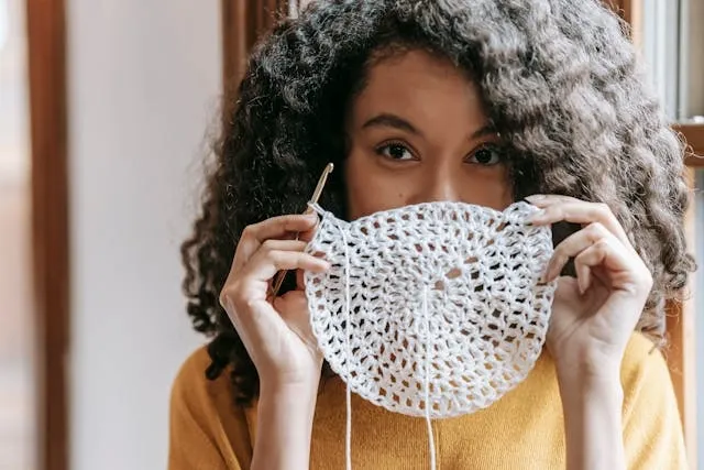 a woman holding a crocheted coaster made from yarn for crochet coasters