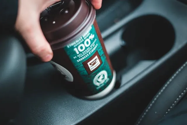 a green and black disposable coffee cup being placed into a cup holder for car coaster sublimation time and temp