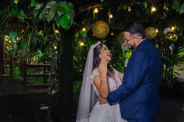 a bride and groom laughing together in a setting with overhanging greenery and lights for personalized wedding ideas