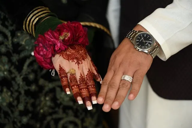 the hands of a bride and groom with elaborate henna patterns and intricate rings for personalized wedding ideas