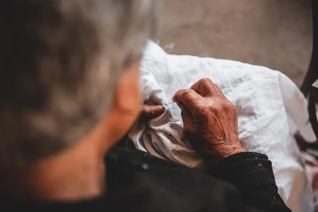 a man embroidering on some white fabric for how to embroider letters