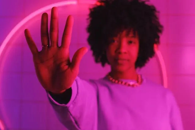 a woman holding her hand up to the camera completely immersed in pink light for neon pink aesthetic