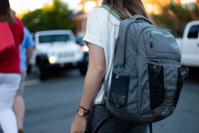 a person carrying a gray backpack while crossing the street for how to organize your backpack