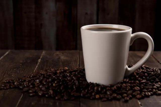 a mug of coffee amid a pile of coffee beans for standard coffee mug size