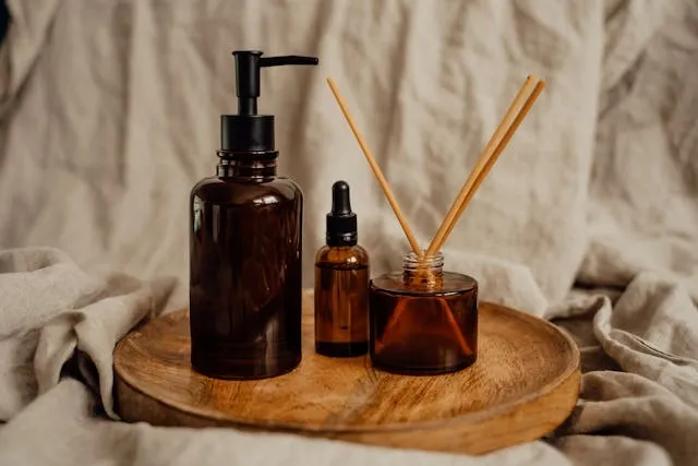 a reed diffuser beside some glass bottles on a wood surface for best car air freshener