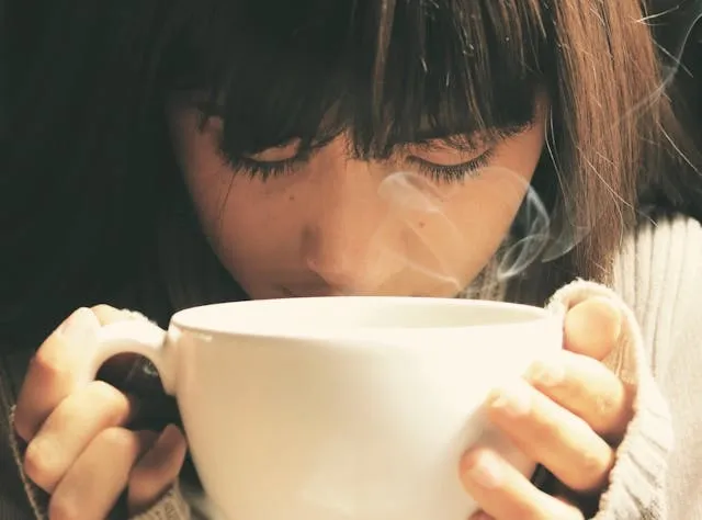 a woman smelling some coffee from a large mug for standard coffee mug size