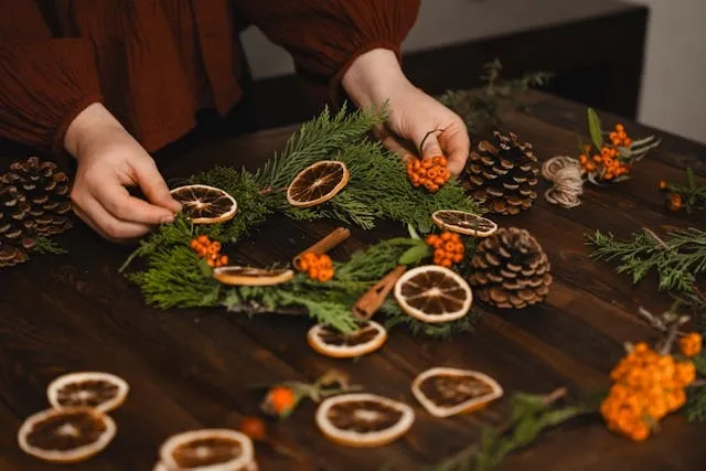 someone making a centerpiece from seasonal greenery and dried fruit for low-cost wedding table decorations