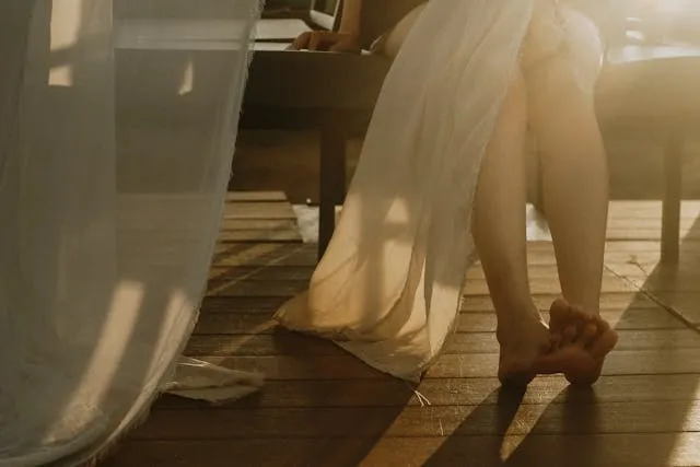 linen draping under a table beside a person’s legs for how to wash linen tablecloth