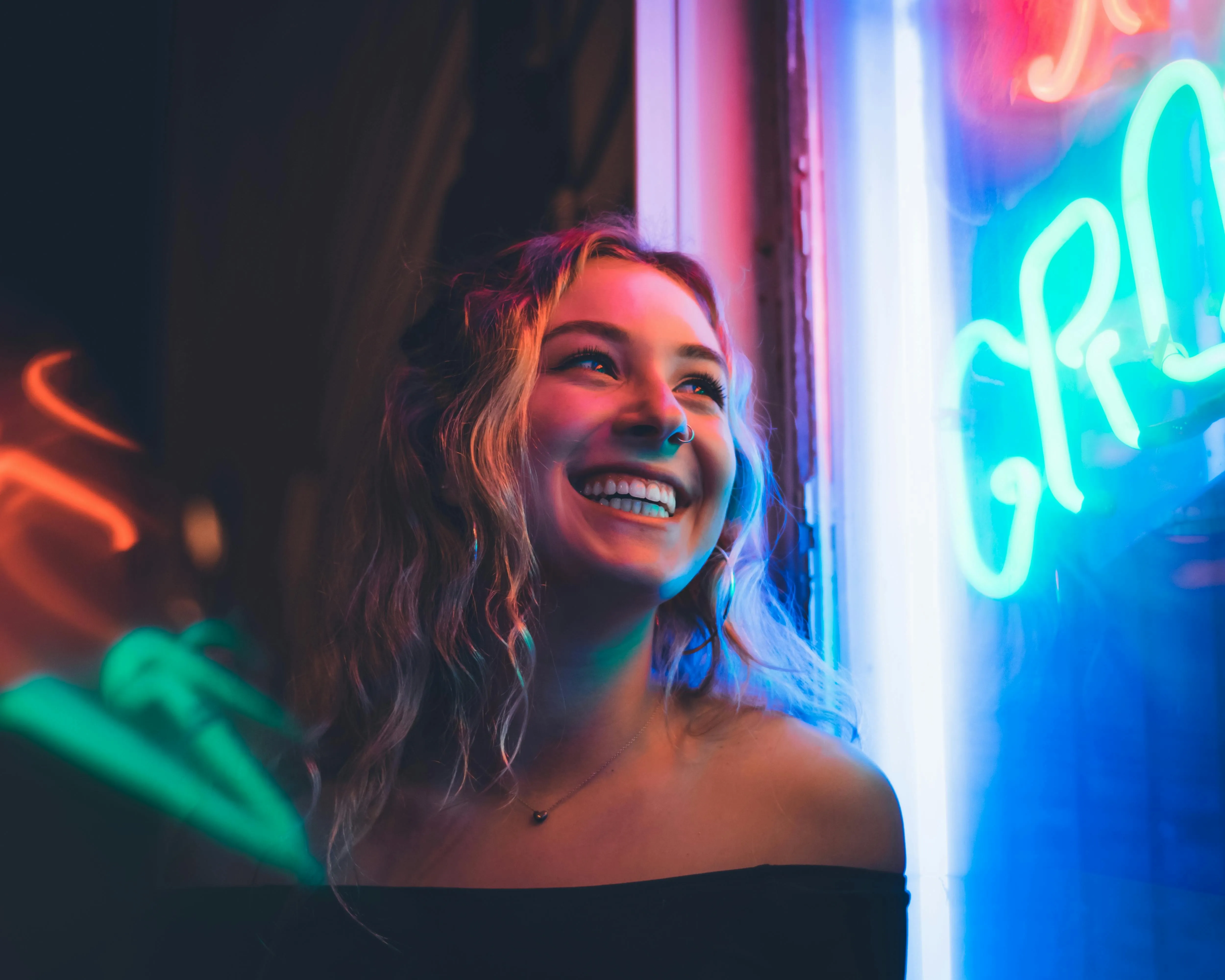 a woman smiling beside a neon sign for neon lights captions