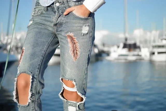 a woman wearing jeans on a pier with an embroidered feather design for creative ways to patch jeans