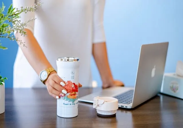 a woman at a desk holding a white tumbler for tumbler engraving ideas