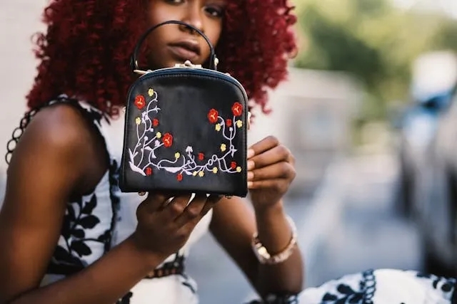 a woman holding a black purse with embroidered flowers for best embroidery machine