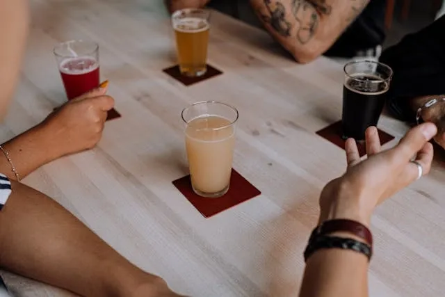 four drink glasses on coasters on a wooden table for how to use a coaster set