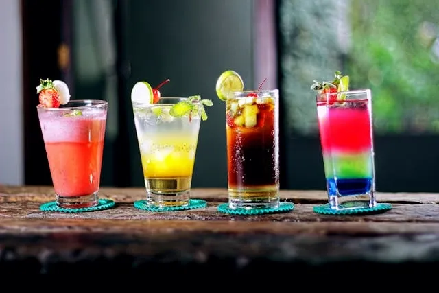 four colorful cocktails on coasters on a wooden table for how to use coaster set