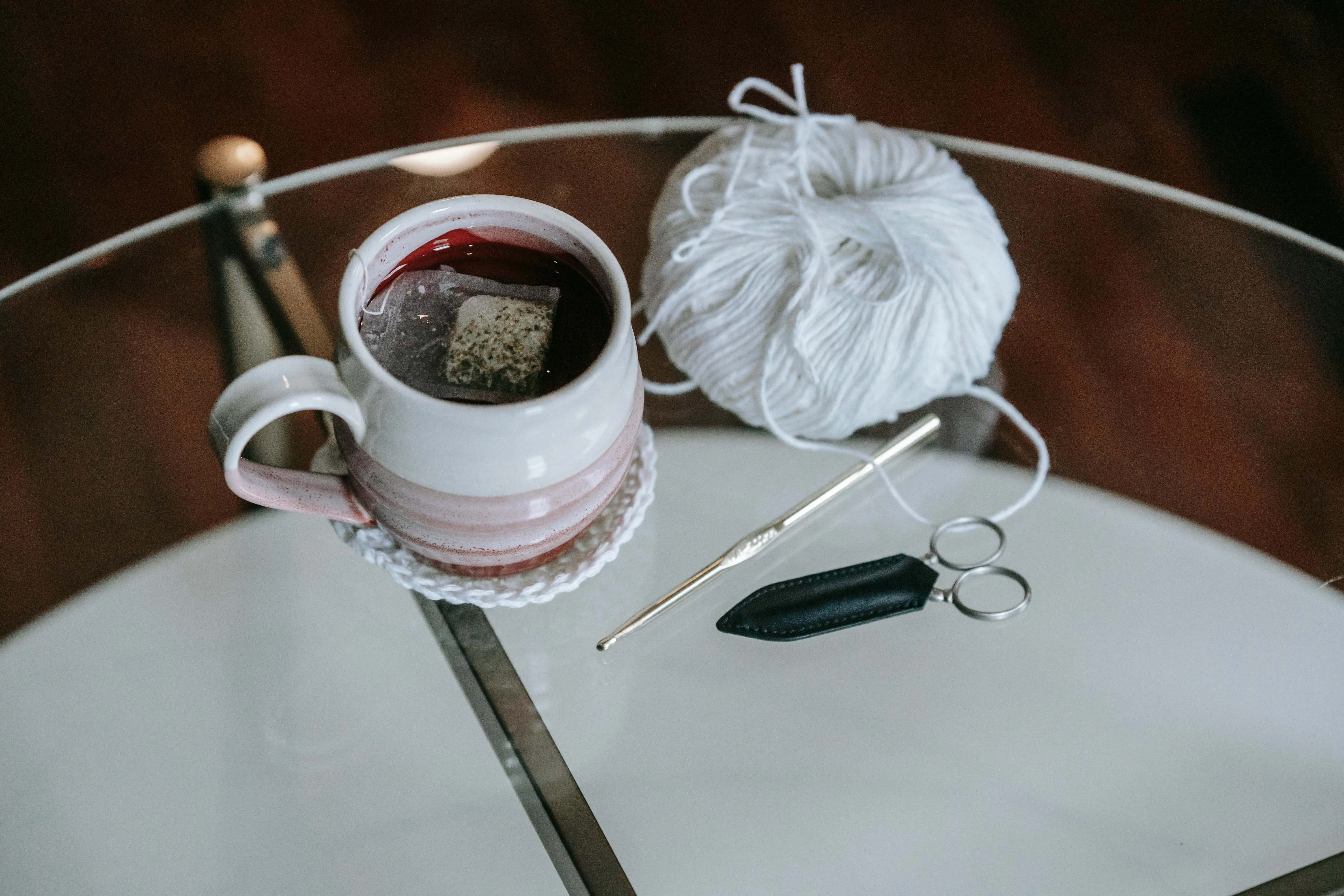 a cup of tea on a knitted coaster beside some yarn for best yarn for coasters