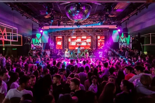 a crowded dancefloor with purple and green lights for nightclub lighting ideas