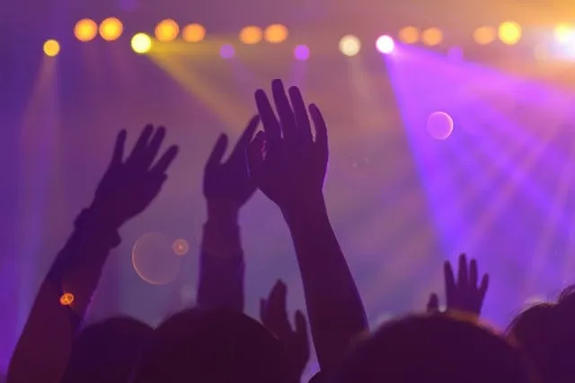 raised hands in front of colorful lights for nightclub lighting ideas