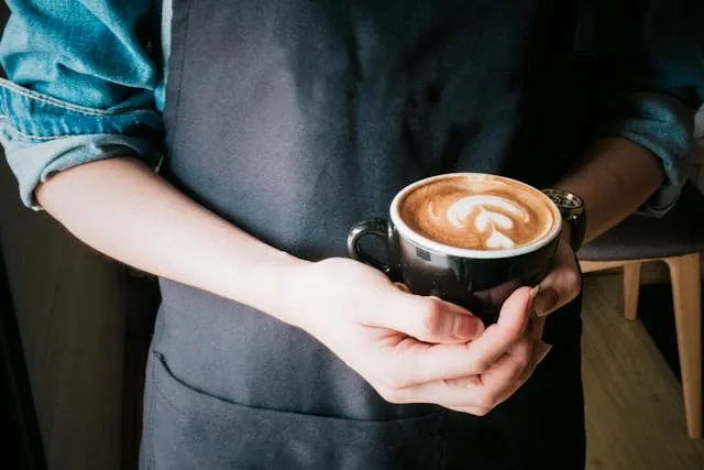 a person holding a mug of cappuccino for porcelain vs ceramic mugs